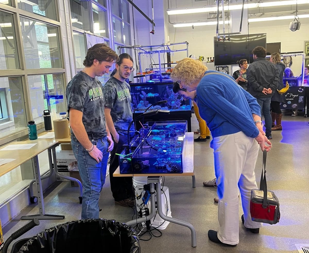 MSMHS students and staff stand in front of a coral tank.