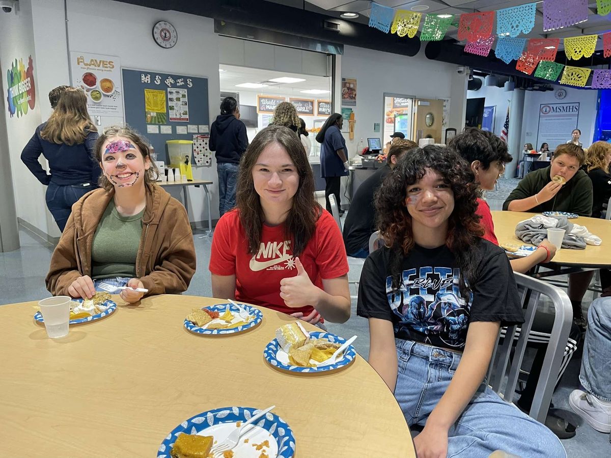 Students sit around a table with Hispanic dishes.